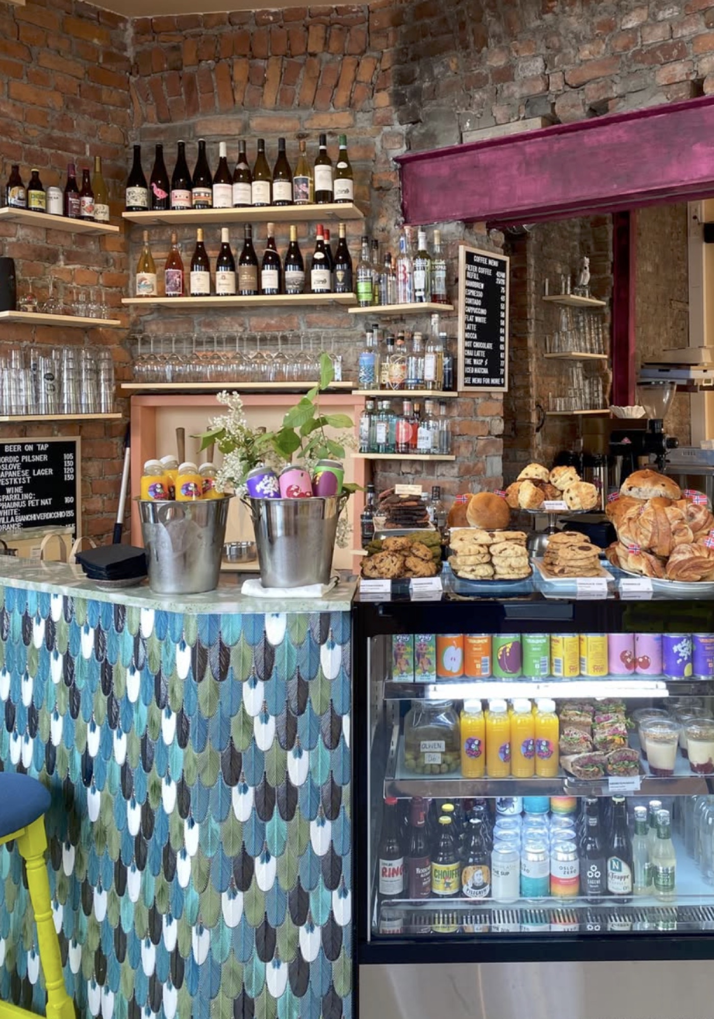 The feather-patterned counter at Papegøye, exposed brick shelves of wine and spirits behind, pastries laid out under the coffee menu board