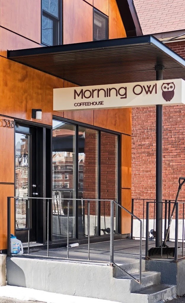 The Morning Owl Coffeehouse entrance on Rochester Street, with the owl logo sign above the door and a wheelchair accessible ramp leading up to the glass storefront