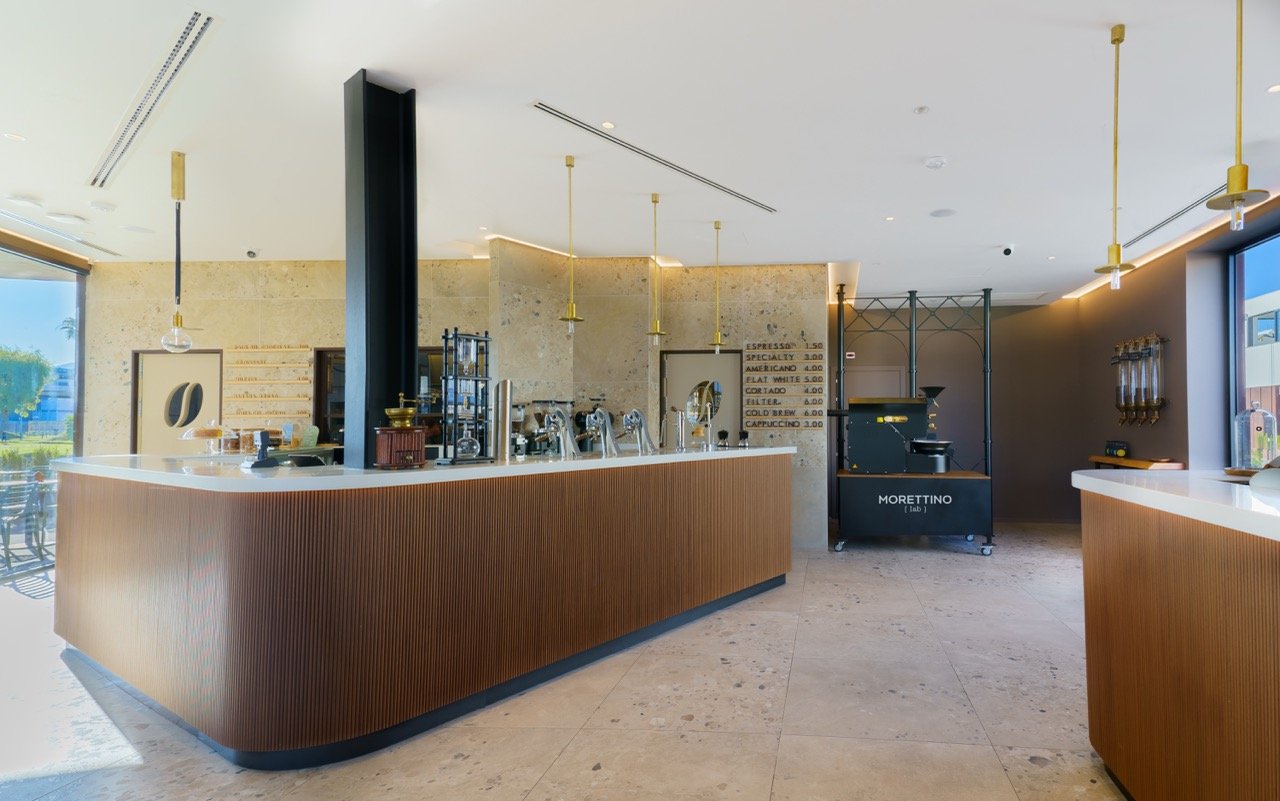 The counter at Morettino Lab with a Modbar espresso setup, brewing gear, and the roaster visible against a stone wall