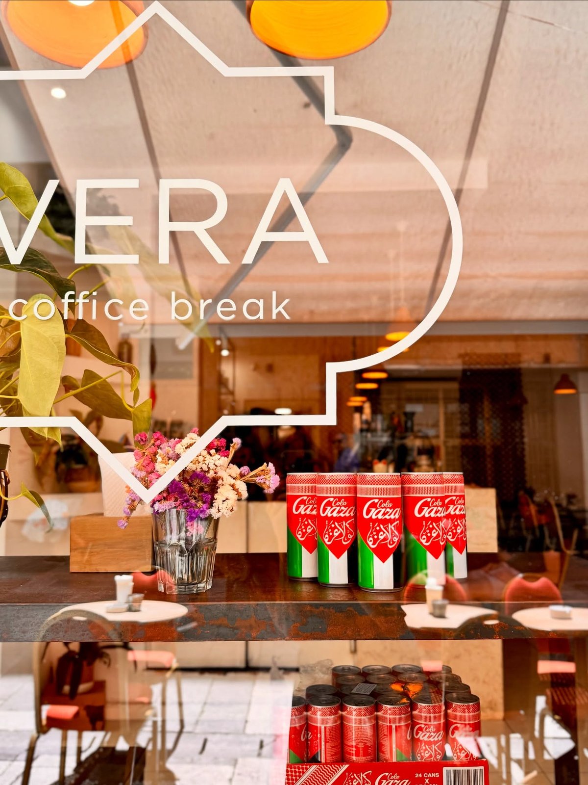 The etched glass window of Vera Coffice Break, with dried flowers and a table visible through the storefront