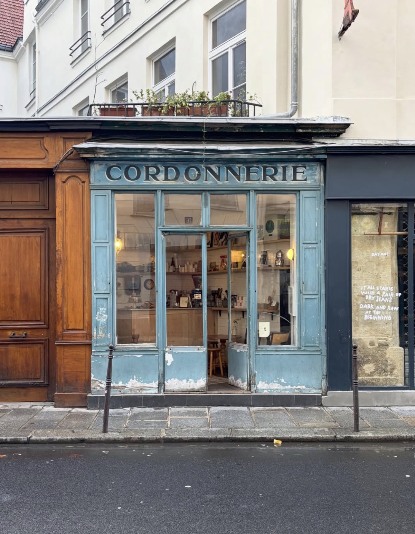 The weathered blue 'Cordonnerie' storefront of Boot Café, shelves and a small counter visible through the open door