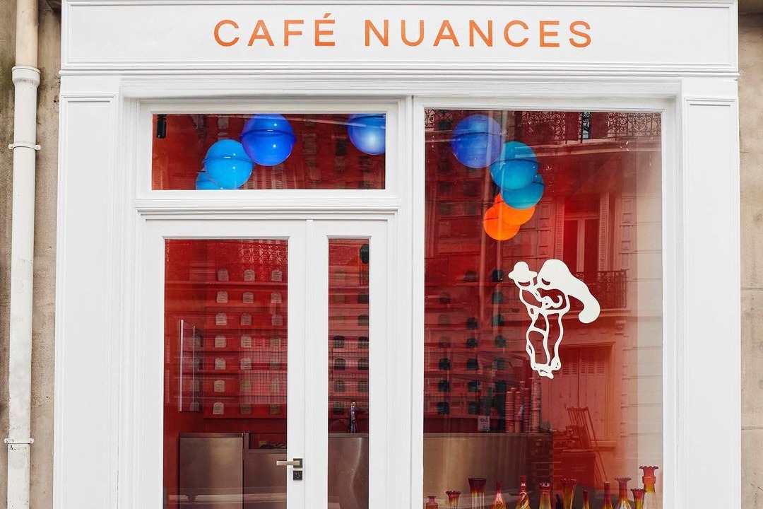 The white Café Nuances storefront on Rue de la Trémoille, orange lettering above windows with blue and orange glass balloon ornaments