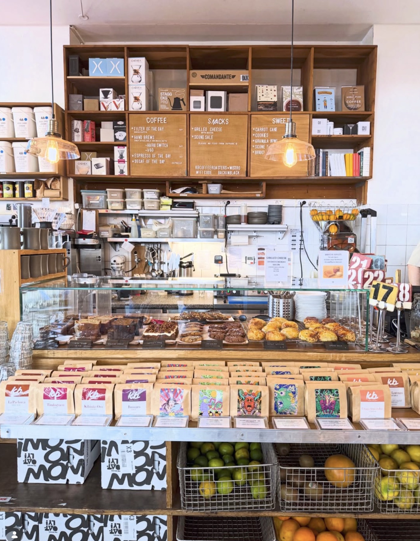 The retail counter at KB CoffeeRoasters, rows of bagged single-origin coffee below a pastry case and shelves of brewing gear