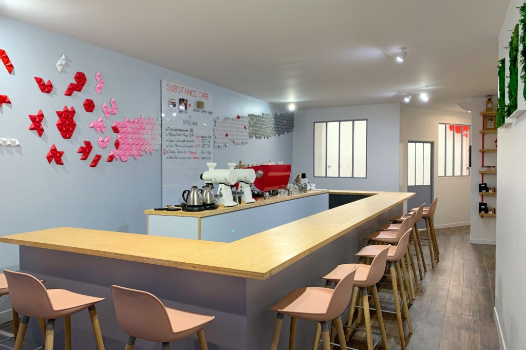 The U shaped counter at Substance Café, a red two group Slayer machine on the bar with pink stools and a wall of folded paper hearts