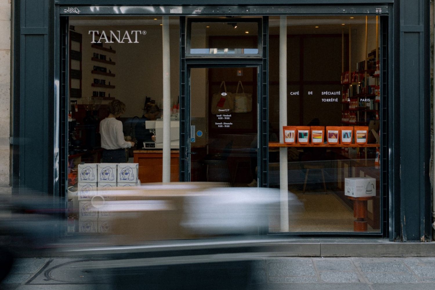 The TANAT storefront on Rue Tiquetonne, baristas at the counter and rows of orange coffee bags displayed on a shelf