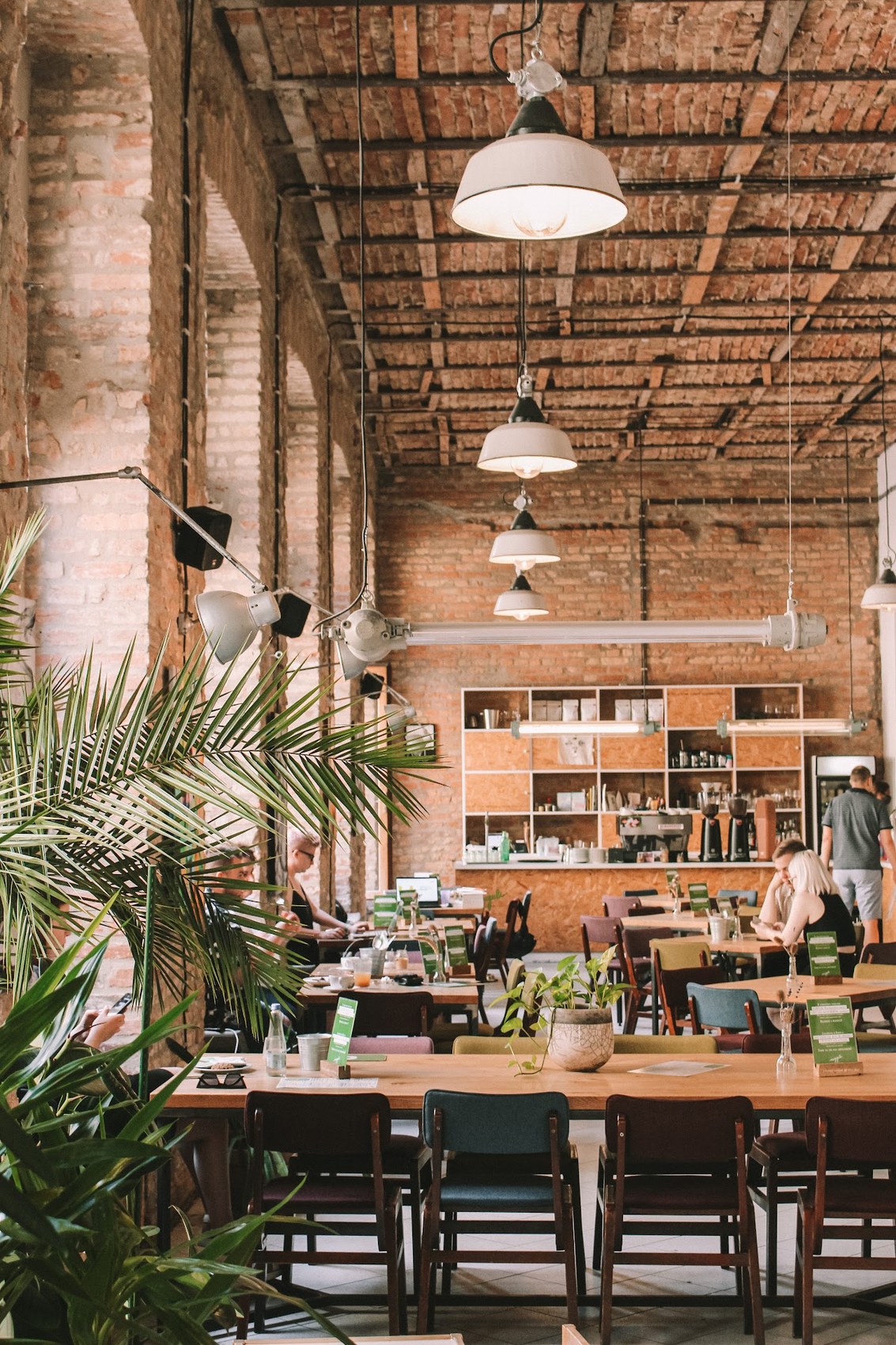 The industrial dining room at Reggeli, with a brick vaulted ceiling, pendant lights, and a coffee bar lined with grinders and espresso equipment