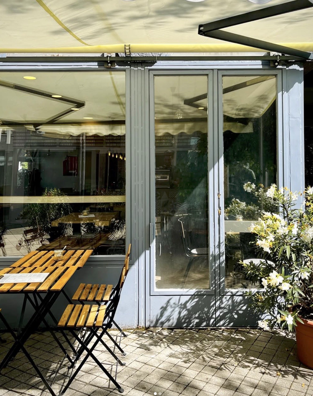 The patio outside Rokusch, with wooden bistro tables and chairs under a yellow awning