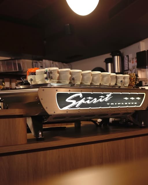 The retro-branded 'Spirit' espresso machine and cup stack on the wooden counter at Howard's Groove