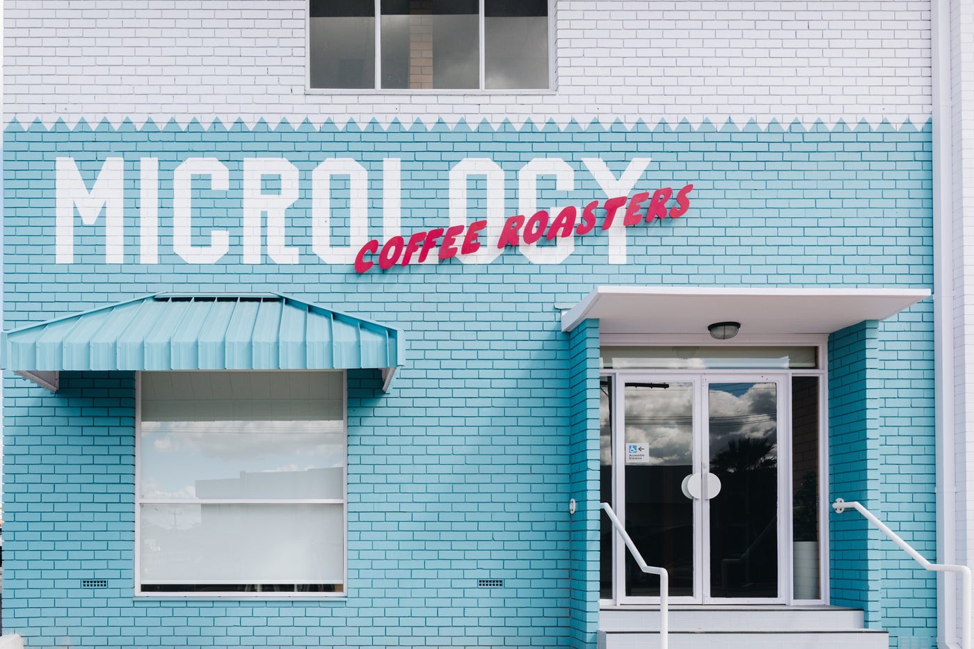 The turquoise brick storefront of Micrology Coffee Roasters, with the shop's name painted in bold letters above the entrance