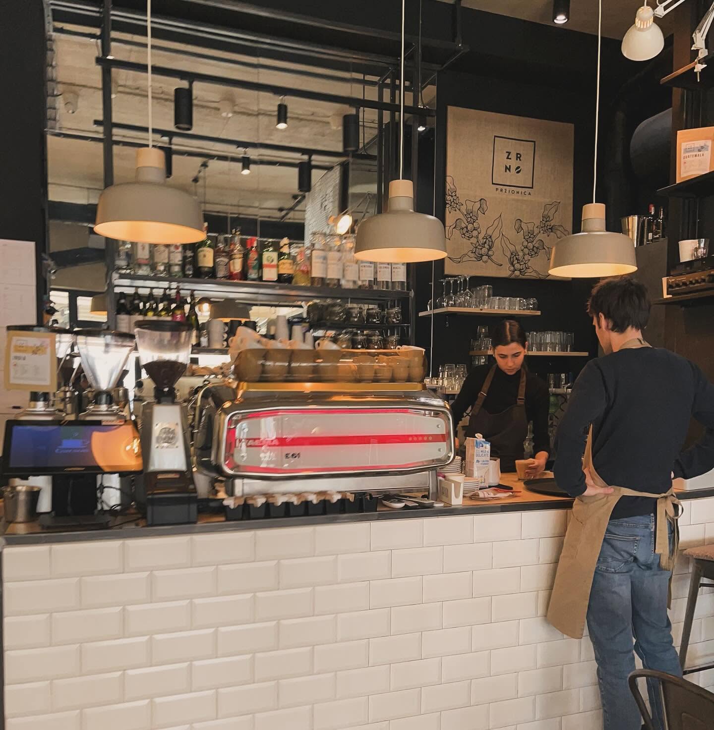 The white subway tiled espresso bar at ZRNO with staff working behind the counter and the ZRNO Przionica sign on the wall