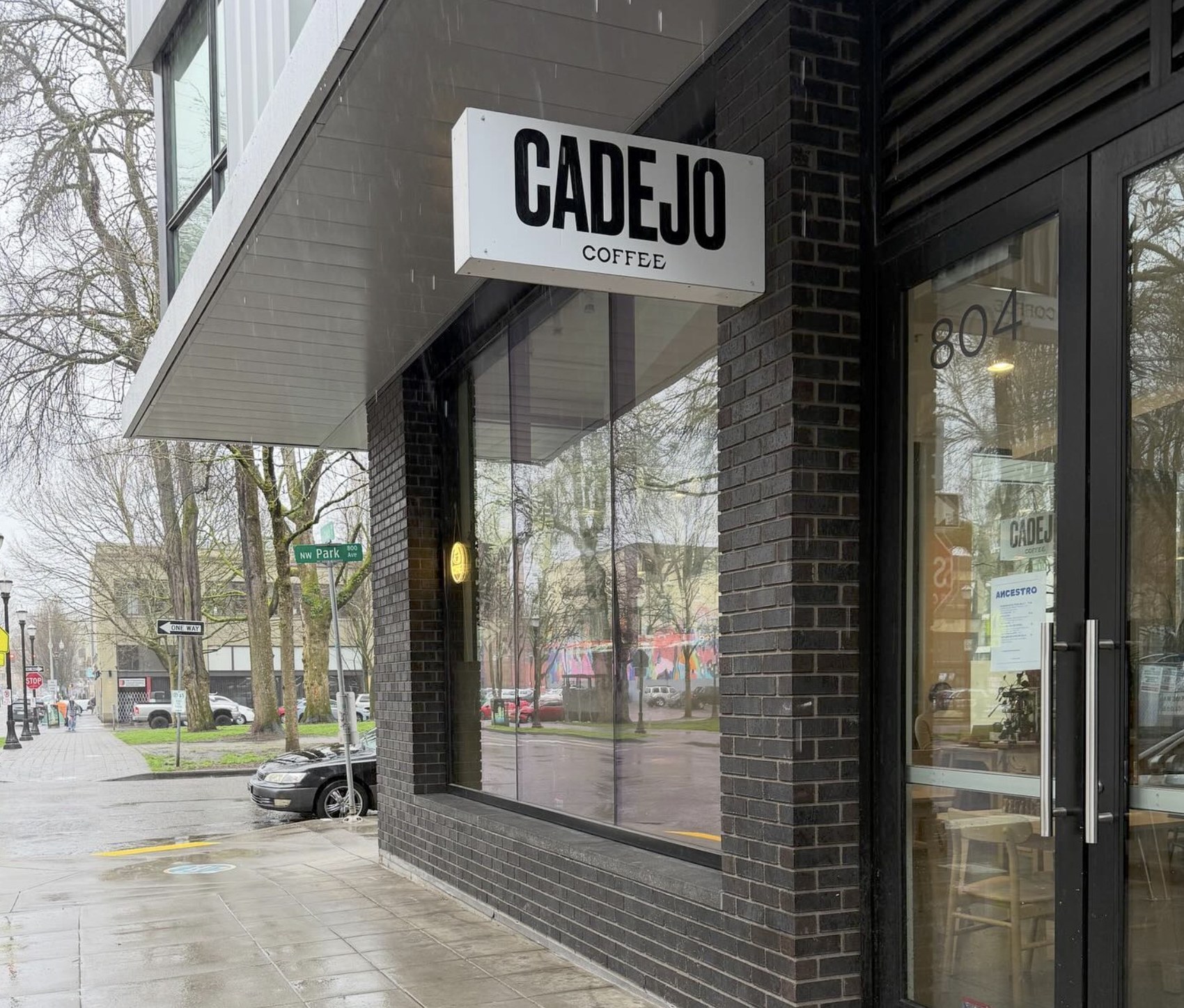 The CADEJO COFFEE sign above the black brick storefront on a rainy NW Park Ave corner