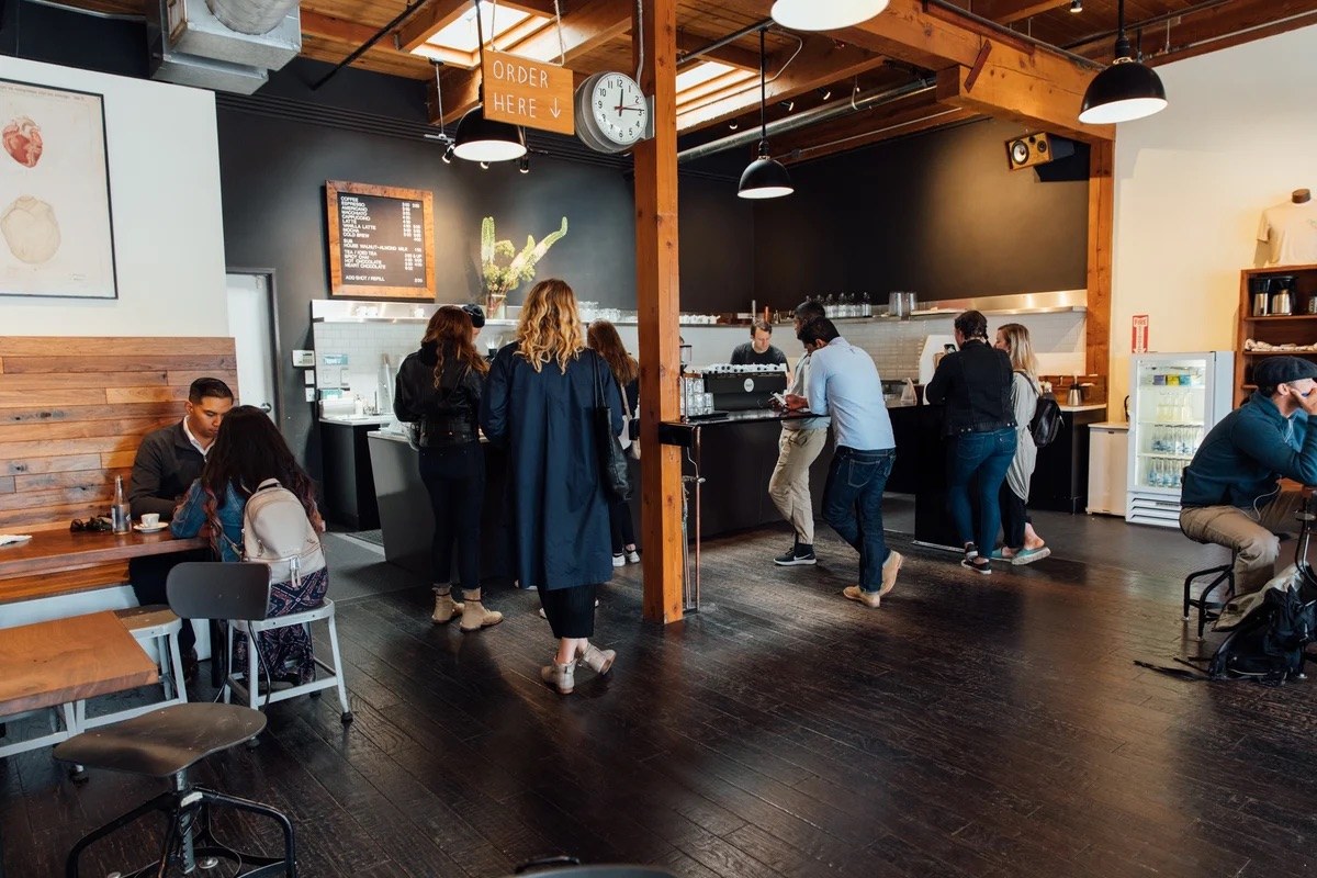 The Burnside cafe's order counter under an ORDER HERE sign, customers in line beneath exposed wood beams