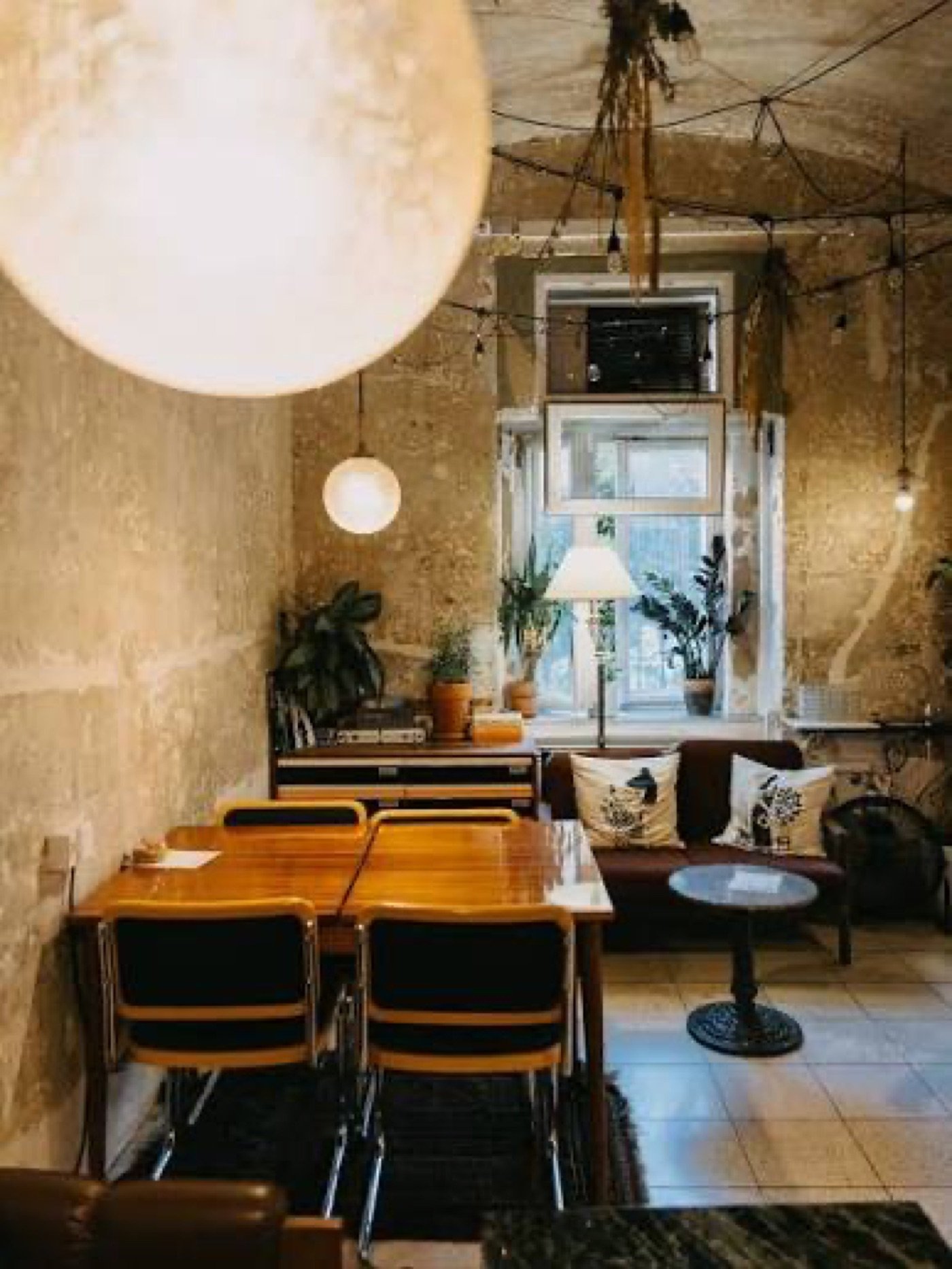 A cozy corner at Format with a leather sofa, houseplants, and string lights under exposed plaster walls