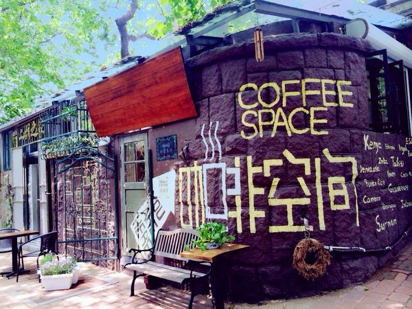 The shop's stone exterior hand painted with COFFEE SPACE and its Chinese characters, a wooden awning over the doorway and a bench out front