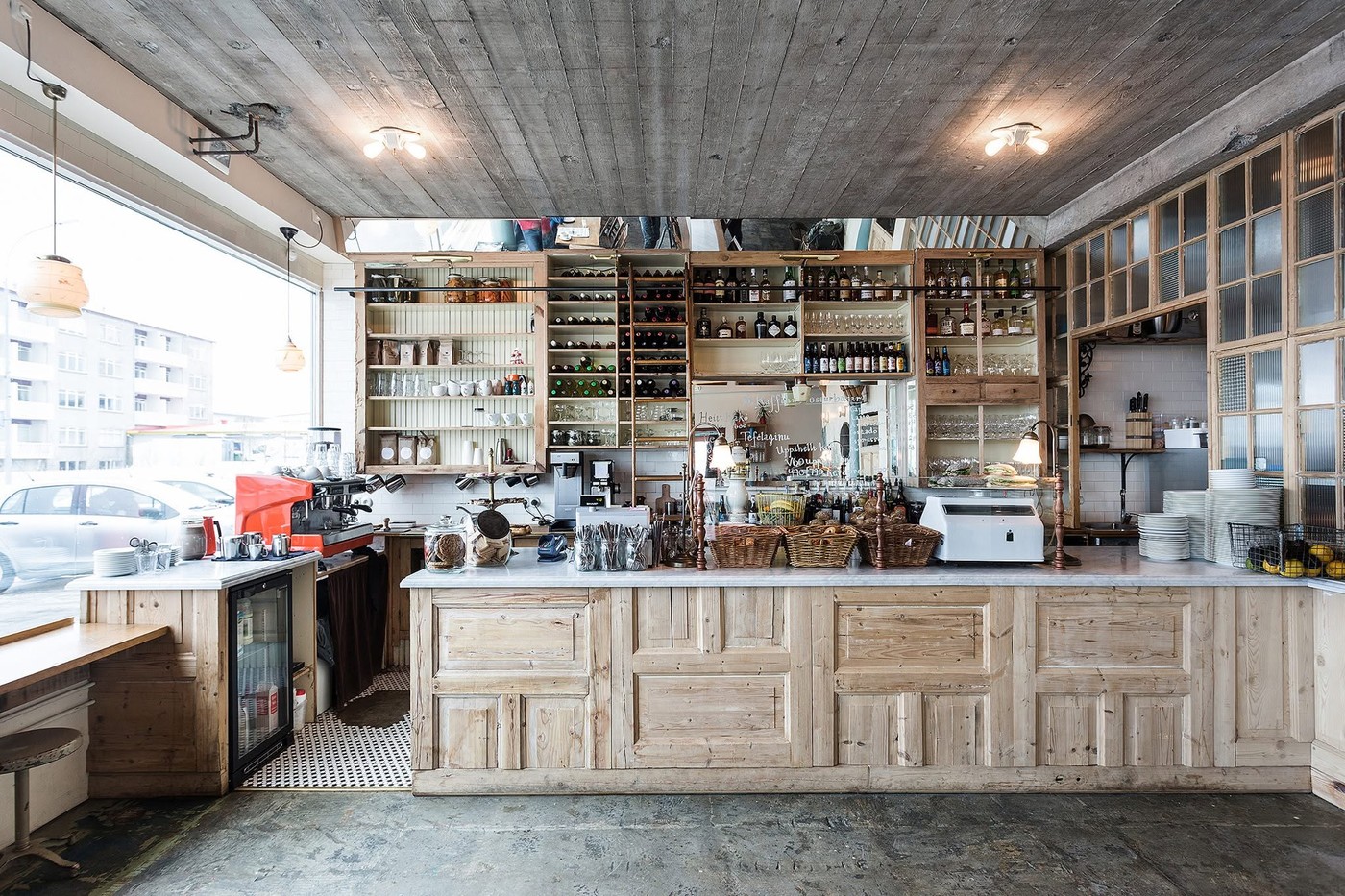 The reclaimed wood counter and shelving at Kaffihús Vesturbæjar, lined with jars, glassware, and bottles