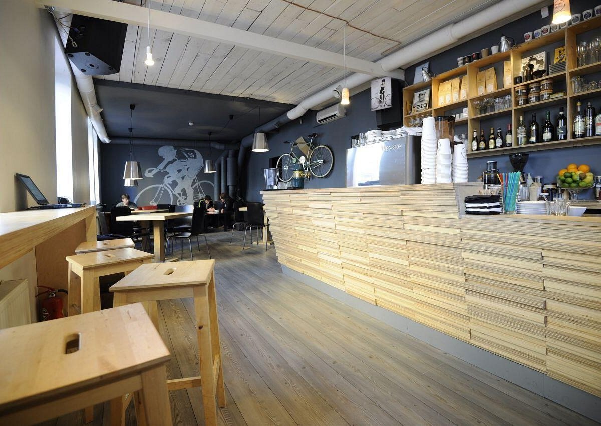 The plywood counter and painted cyclist mural at MiiT Coffee, with retail bags and cups on open shelving behind