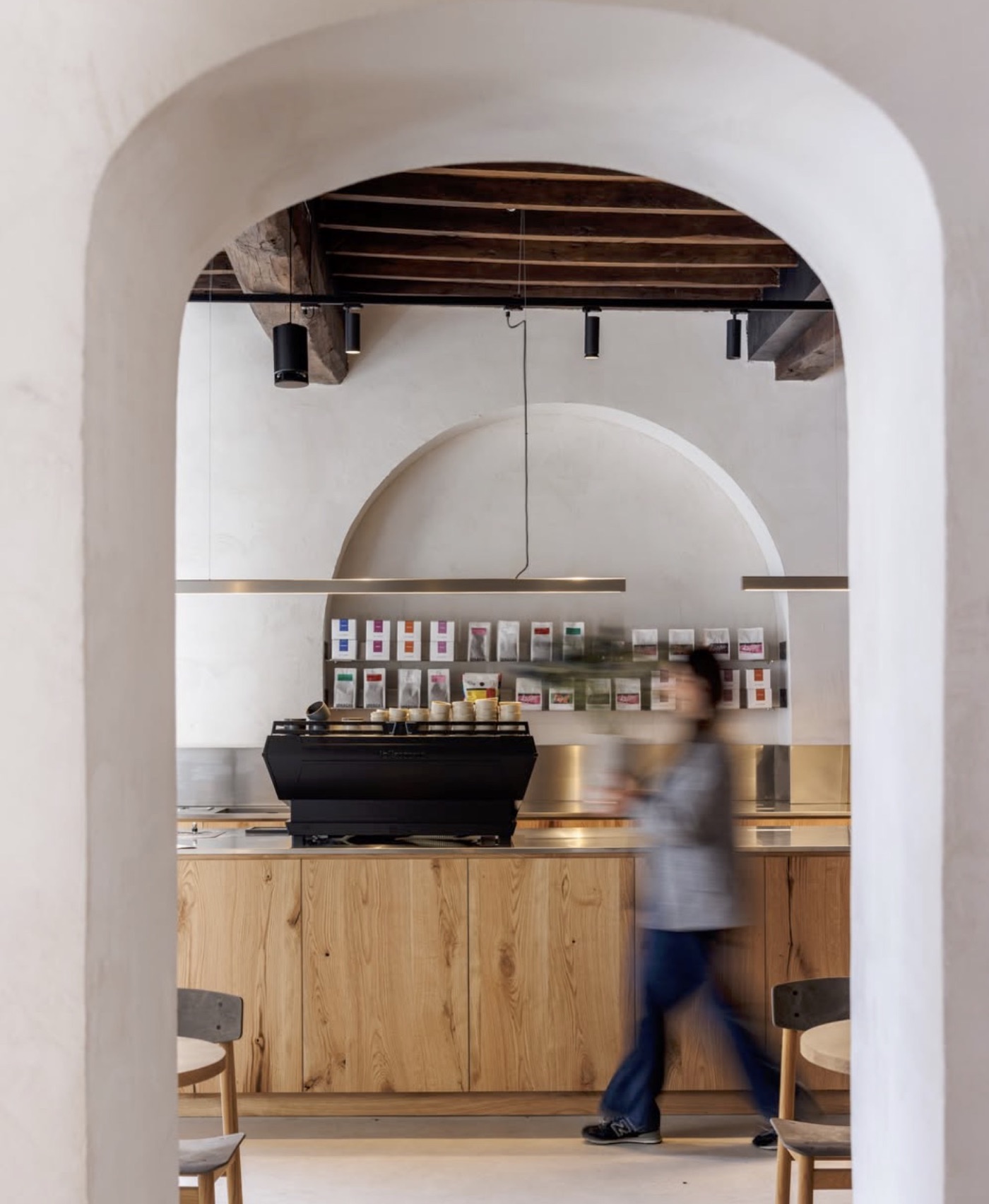 An arched, white-plastered doorway framing the espresso bar at Barnum Cafe, retail coffee bags on the shelf behind