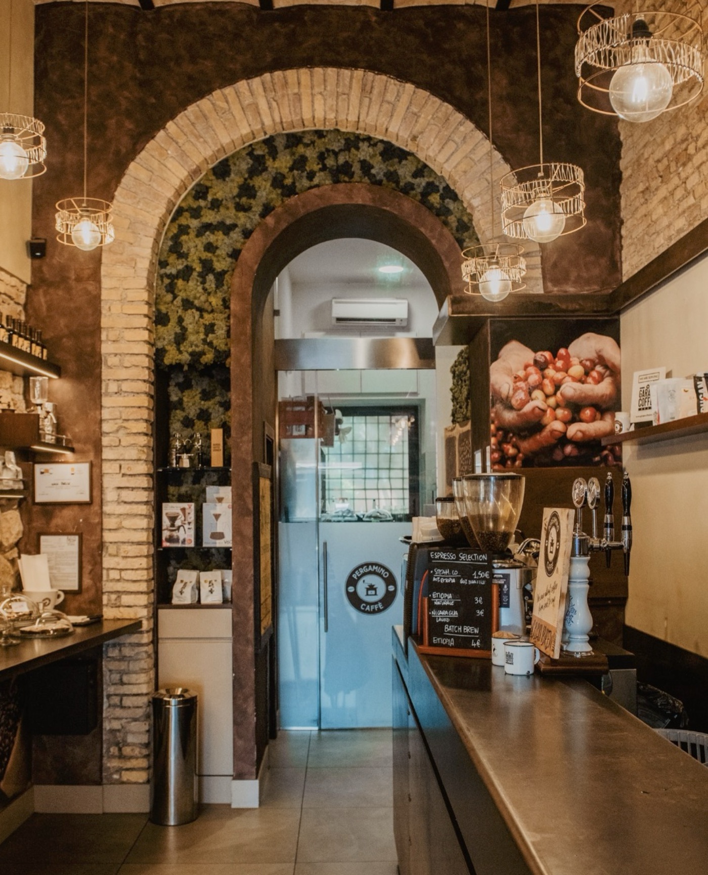 The brick-arched interior of Pergamino Caffe, the round 'Pergamino Caffe' badge on a glass door and an espresso menu chalkboard by the counter