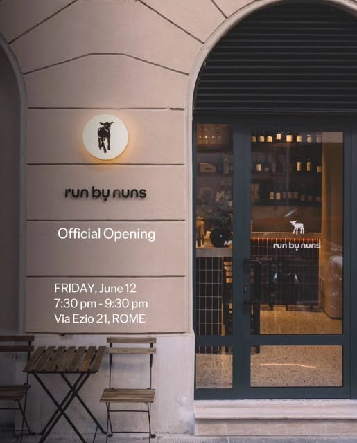 The arched storefront of Run by Nuns on Via Ezio, glowing warmly at dusk