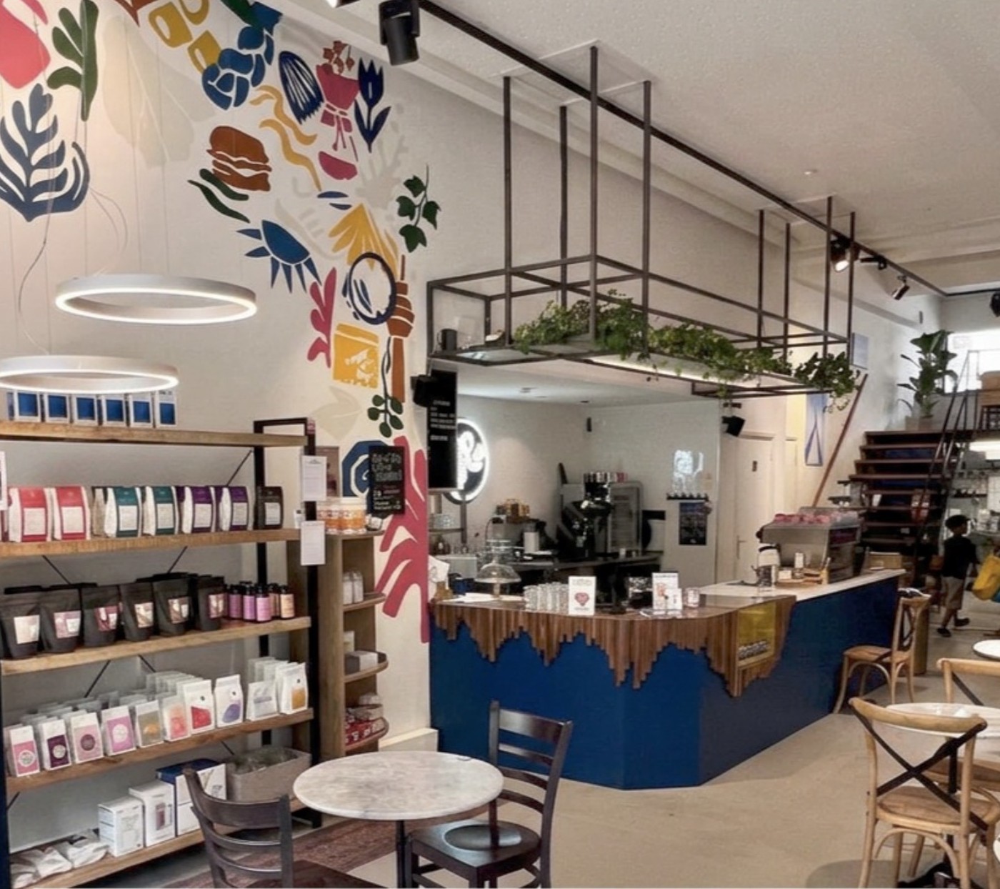 The colorful mural and retail shelves of coffee bags beside the blue tiled counter at New Jozi Coffeehouse