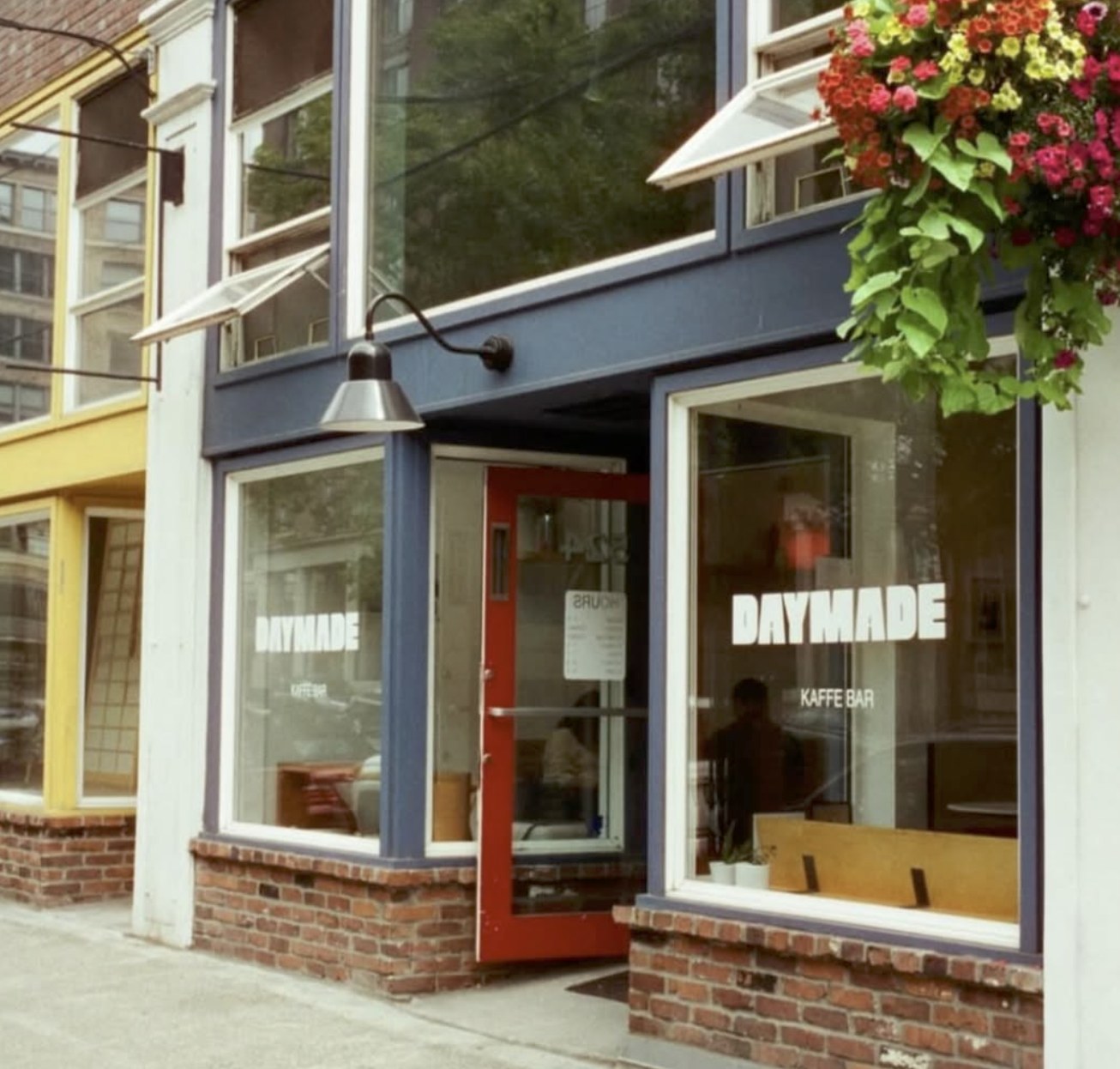 The blue storefront at Day Made Kaffe Bar with a flower basket hanging outside