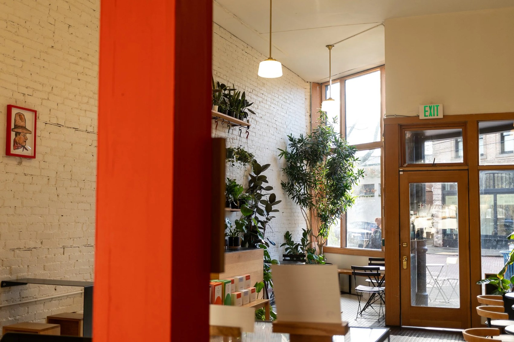 The plant filled interior at Homage Coffee, with white brick walls and hanging pendant lights