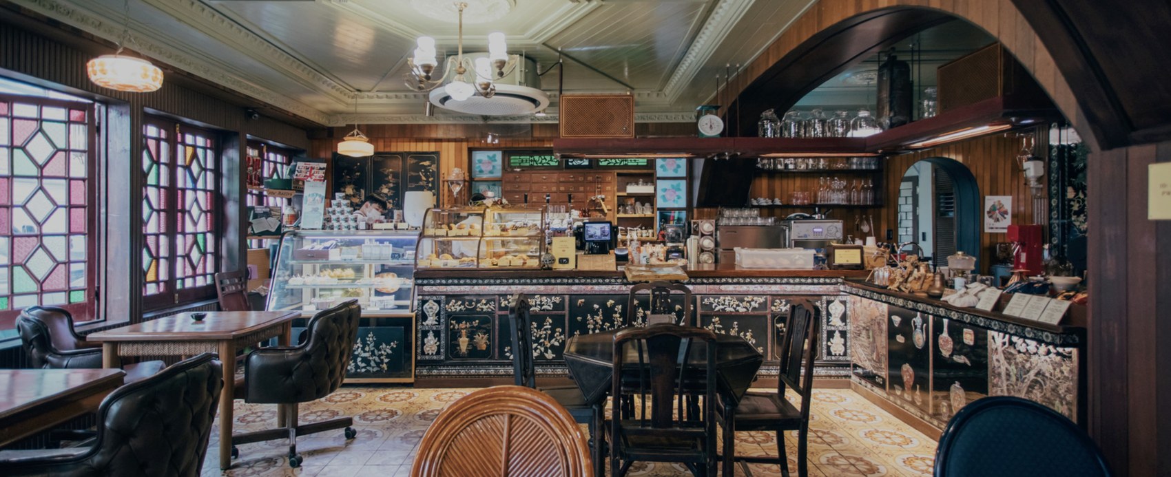 The ornate wood paneled interior of Coffee Hanyakbang, stained glass windows, a mother of pearl inlay counter and a pastry case