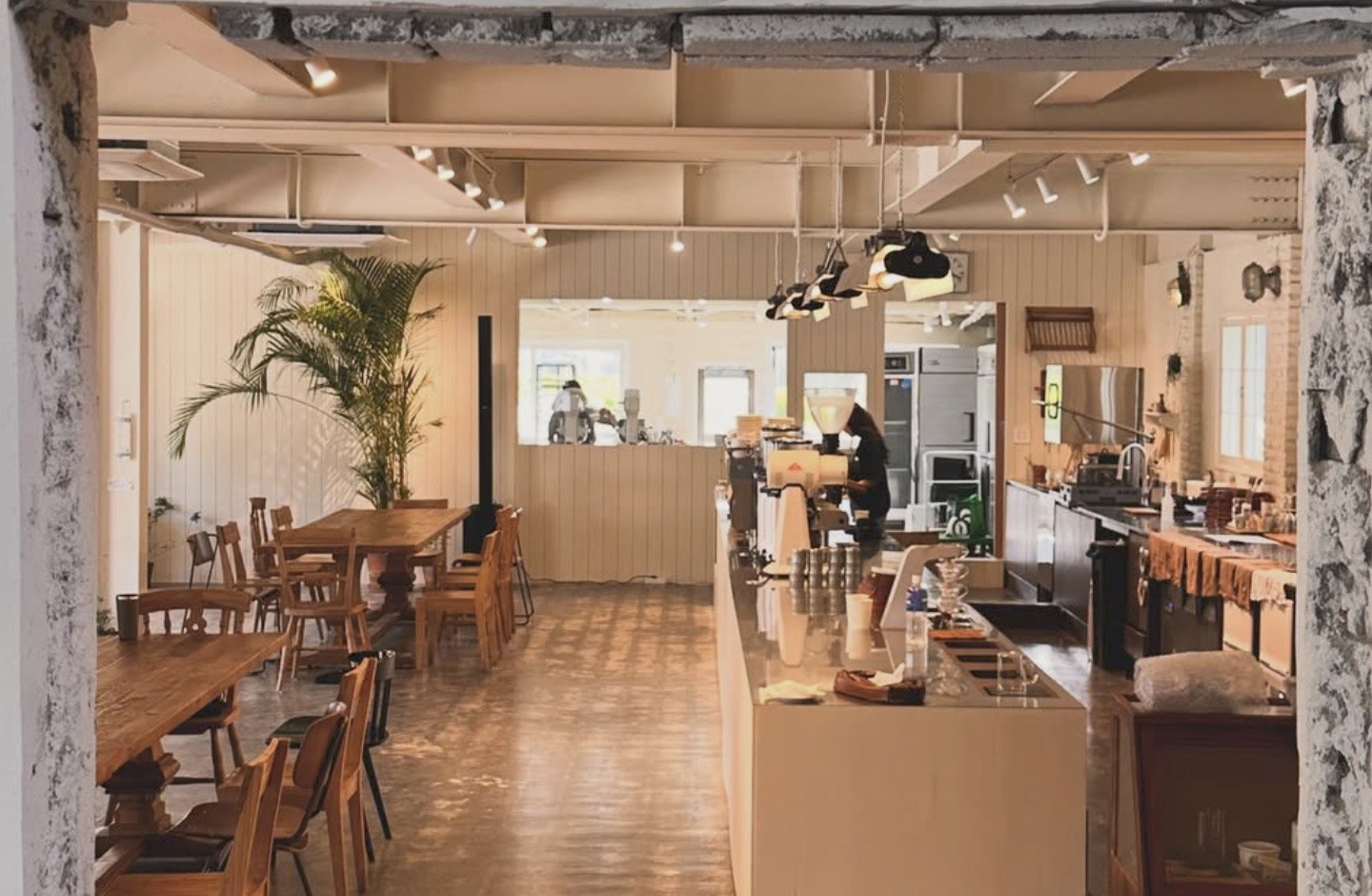 A view through an arched stone doorway into Lowkey's spacious room, wooden tables on the left and the espresso bar on the right