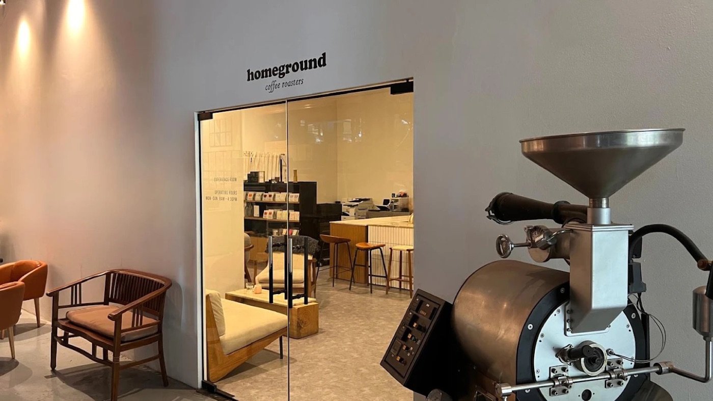 The glass entrance to Homeground Coffee Roasters, a display roaster in the foreground and retail shelving visible inside