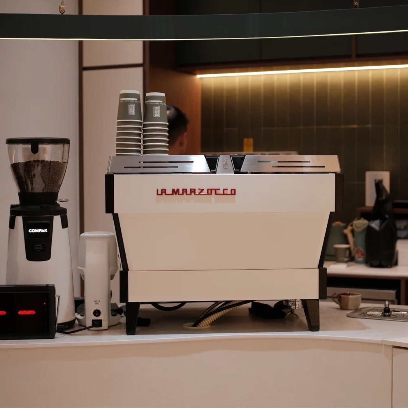 A cream La Marzocco espresso machine and Compak grinder on the counter at Tiong Hoe Specialty Coffee