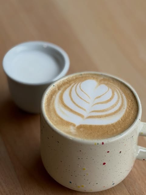Latte art in a speckled ceramic mug on a wooden table at Urban Embassy