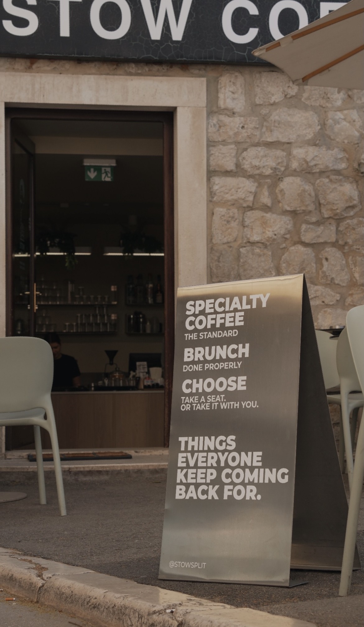 The STOW Coffee storefront sign reading Specialty Coffee, The Standard, Brunch Done Properly beside the open stone walled entrance