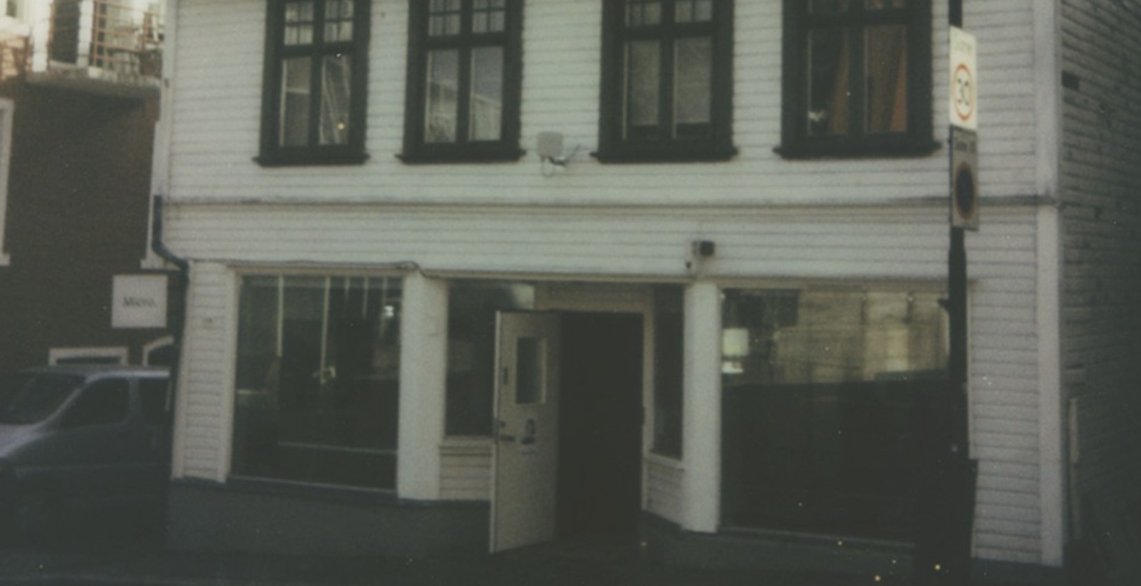A vintage style exterior view of the white wooden building with the Micro Kaffi sign