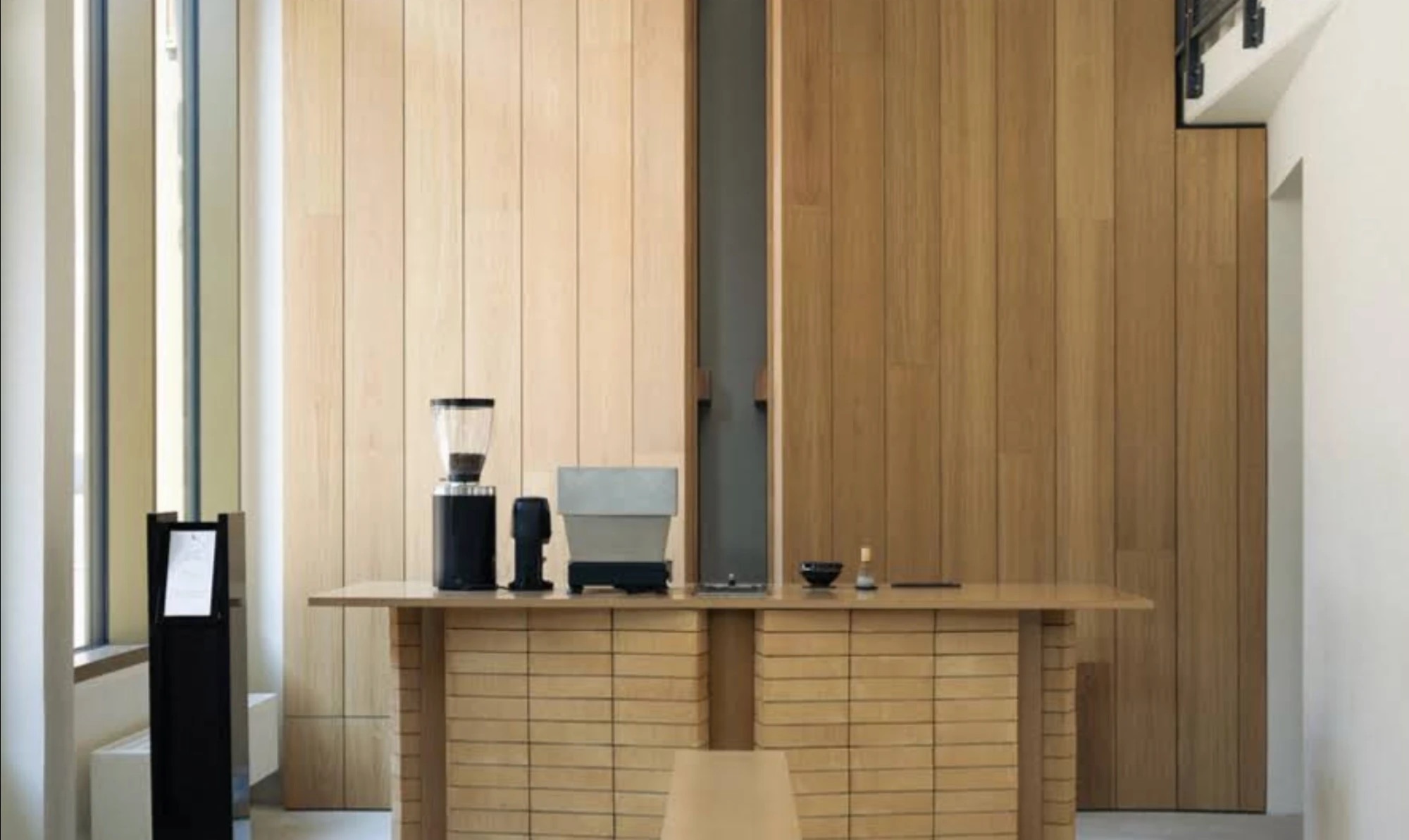 The oak paneled counter at Balue in Stockholm, set with a grinder, scale, and minimalist coffee tools