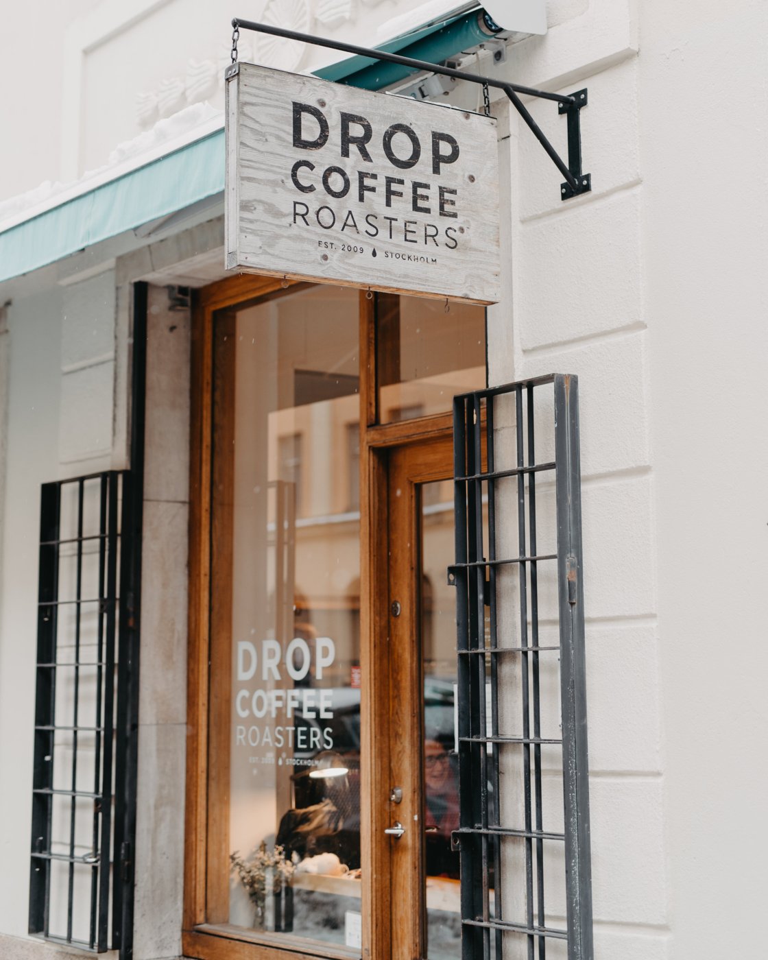 The Drop Coffee Roasters sign hanging above the wood-framed entrance