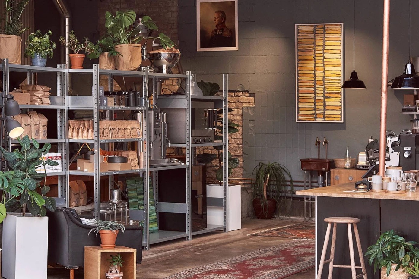 Stockholm Roast's showroom interior, retail shelving stacked with roasted bags and equipment beside a wood counter espresso bar with stools