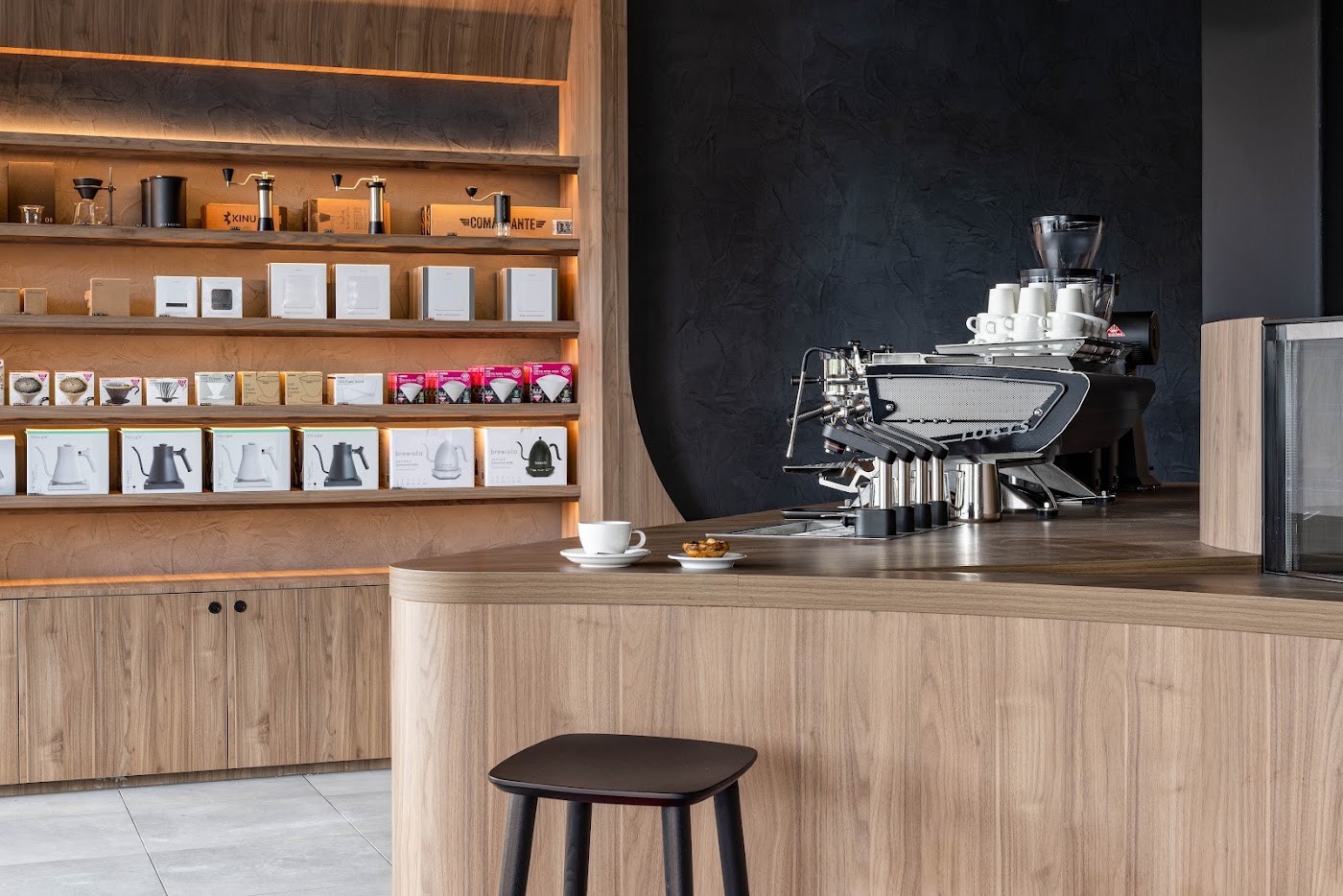 The outward facing espresso machine and curved timber counter at Toby's Estate, with a wall of brewing gear for sale behind