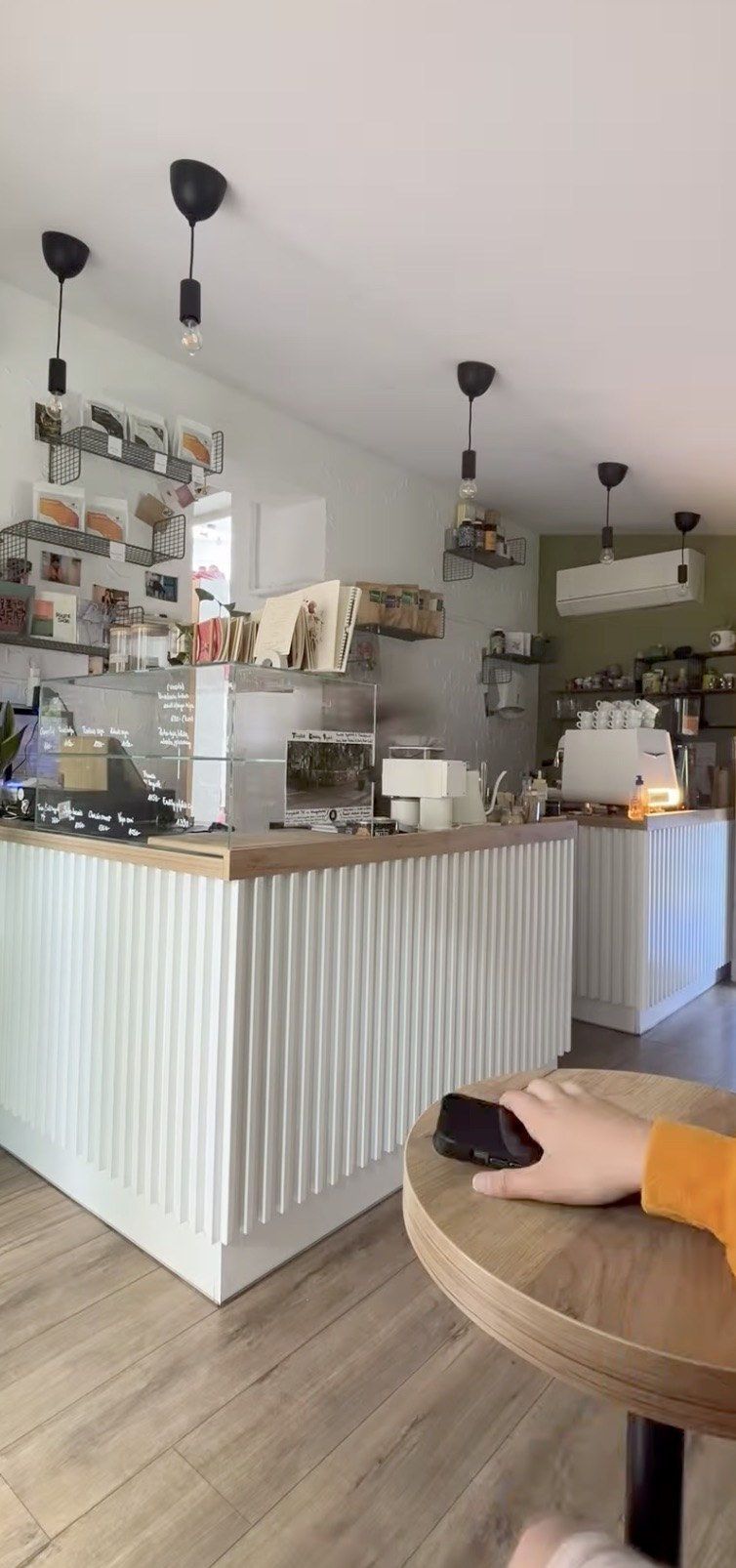 The counter at Daily Dose Café, with a menu board, retail coffee bags on shelves, and pendant lights overhead