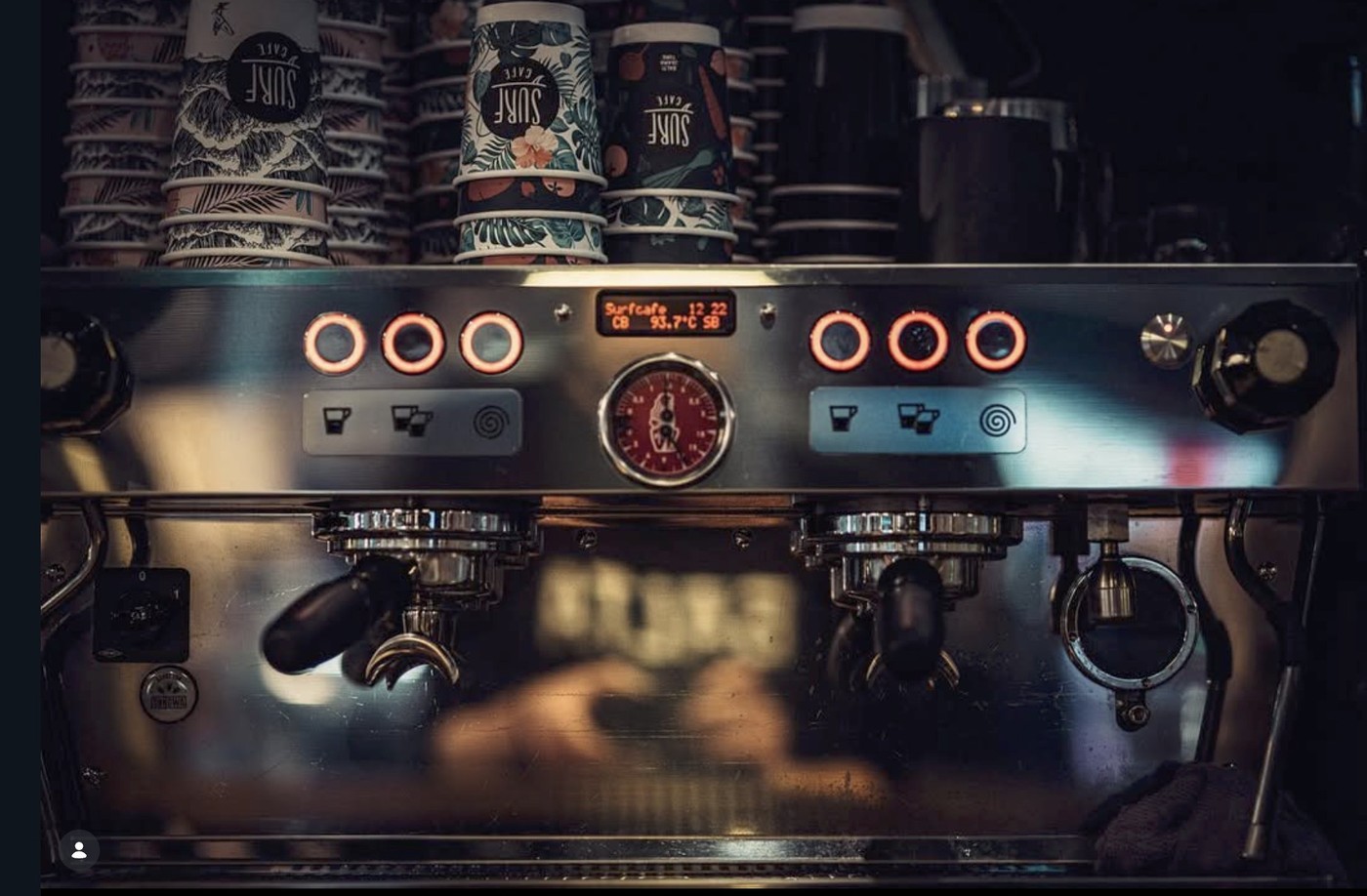 A row of tropical patterned Surf Café takeaway cups stacked on top of the espresso machine