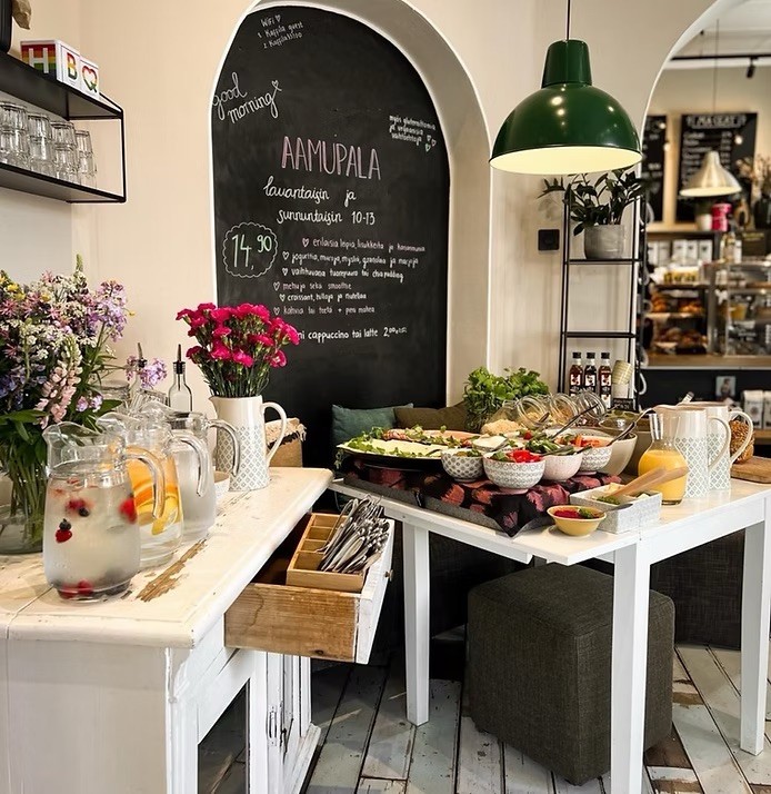 A weekend breakfast spread of salads, yoghurt bowls, and pastries laid out beside a chalkboard menu at Kaffila