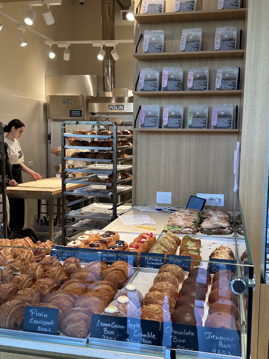 The self serve pastry counter at NOJE bakery with a staff member arranging fresh bread