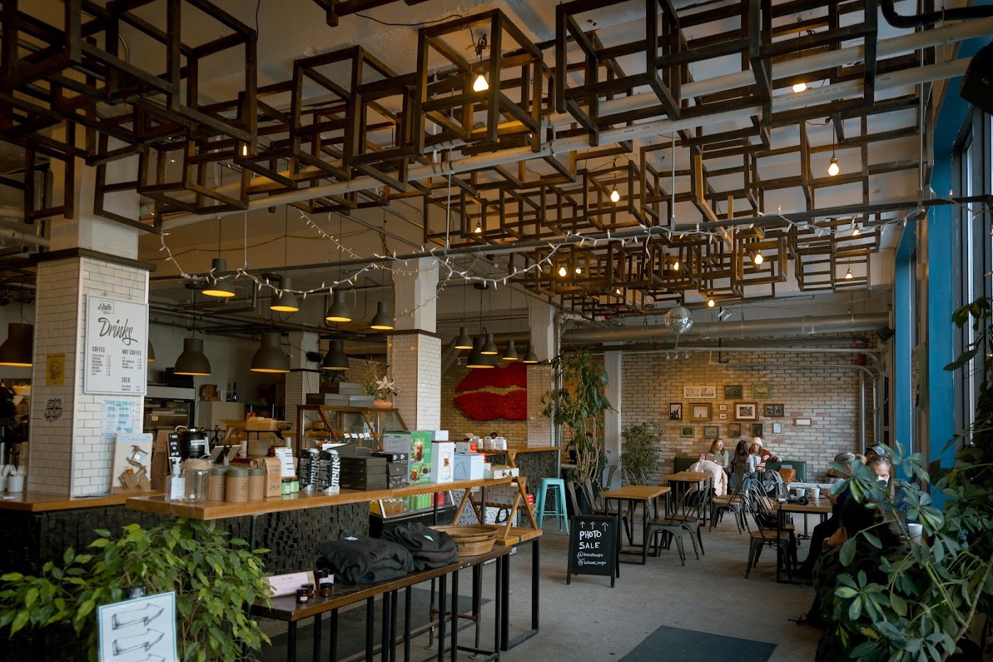 Hale's industrial wooden cube ceiling installation strung with lights above the counter, a Drinks menu board visible below