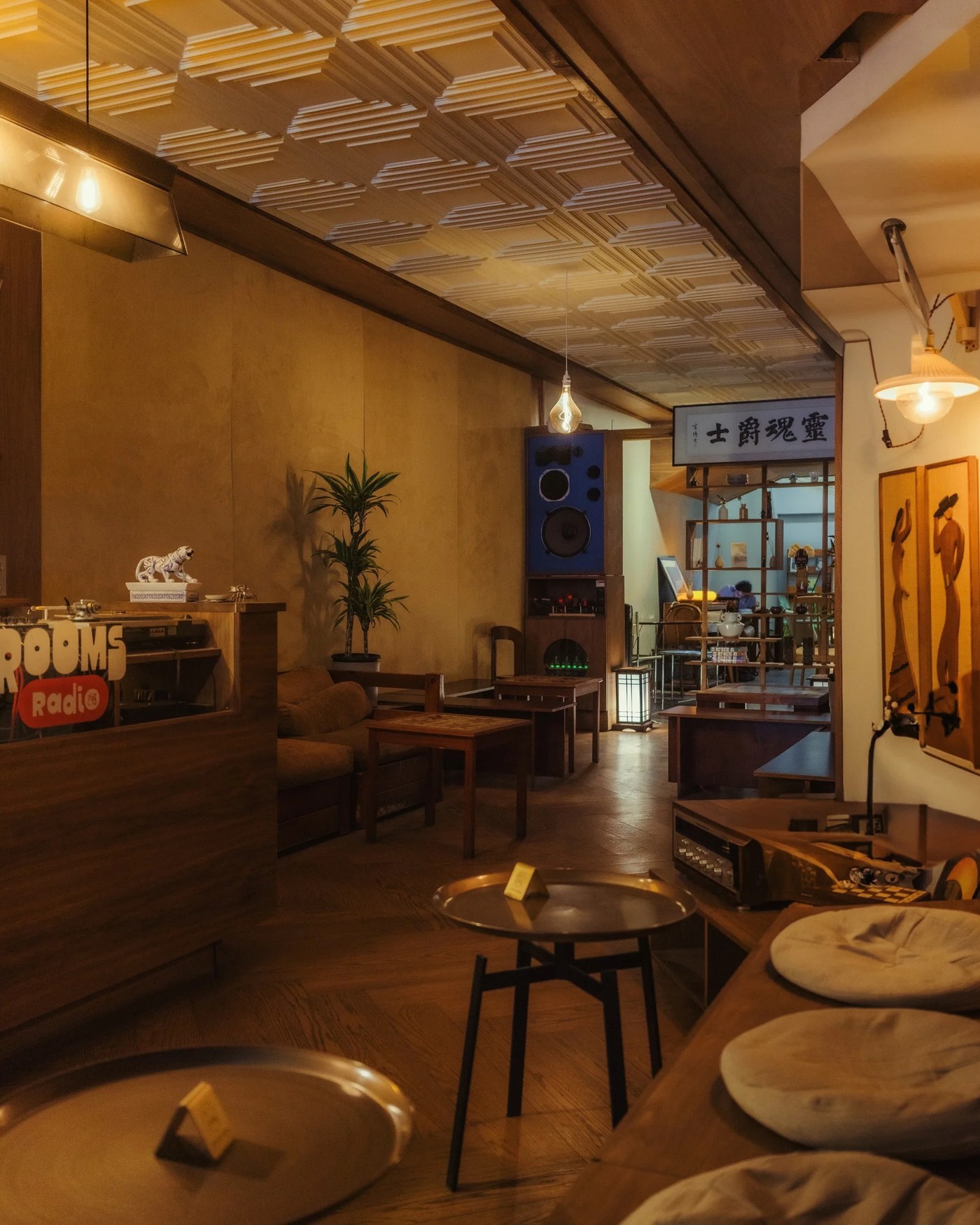 The listening lounge at Rooms with a neon Rooms Radio sign, vintage speakers, a DJ booth, and warm ambient lighting