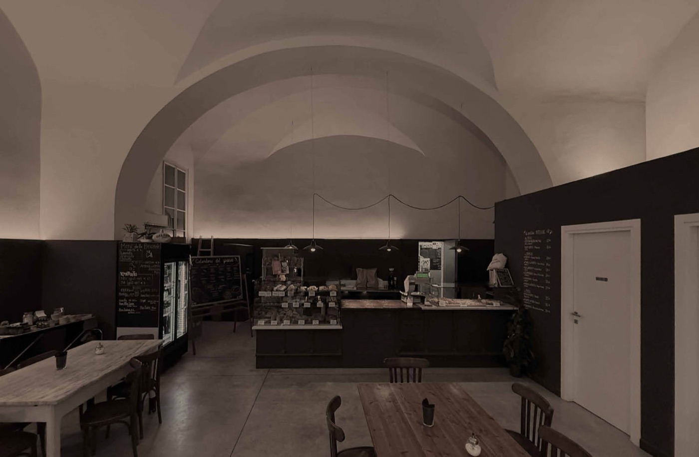 A vaulted ceiling over the bakery counter at Spaccio Pani, pastries and loaves displayed under hanging pendant lights