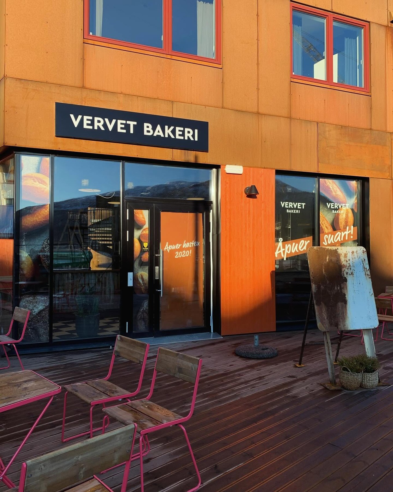 The orange Corten Building storefront with the Vervet Bakeri sign and outdoor deck seating
