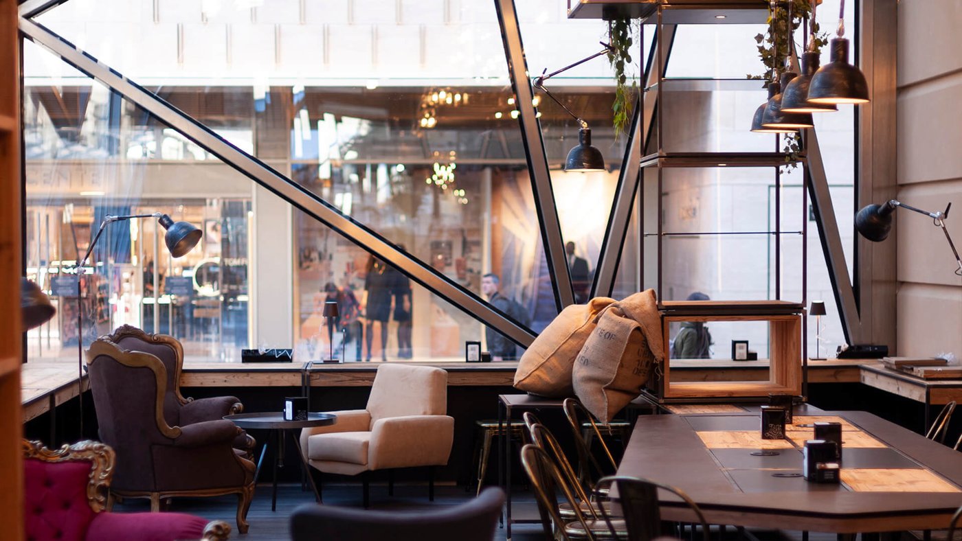 The industrial-showroom interior of Costadoro Social Coffee Factory, exposed steel beams and vintage armchairs