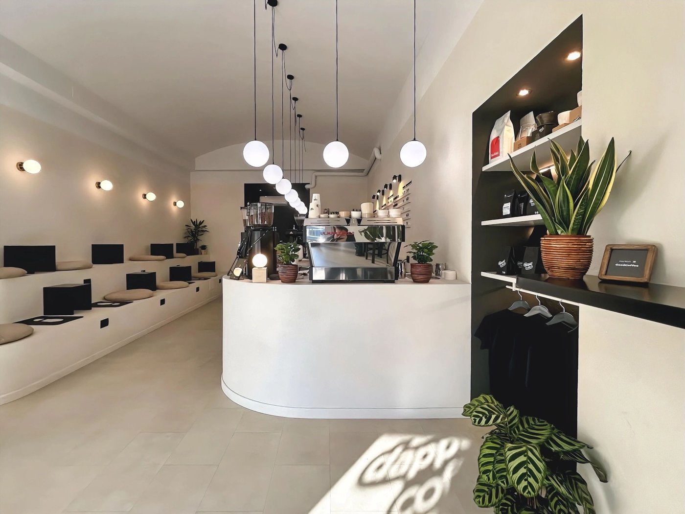 The curved white counter at Dapper Coffee under a row of globe pendant lights