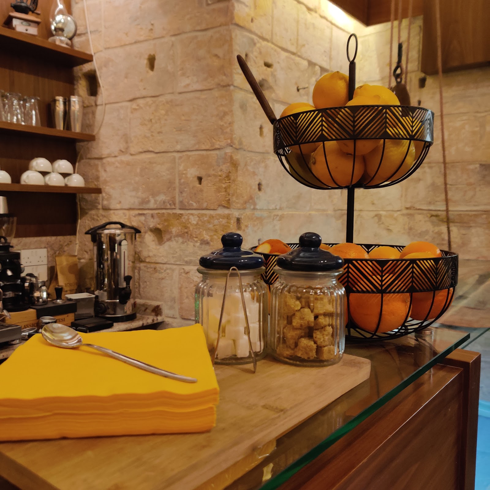 The stone walled counter at Tal-Kafe with baskets of citrus and glass jars beside the coffee station
