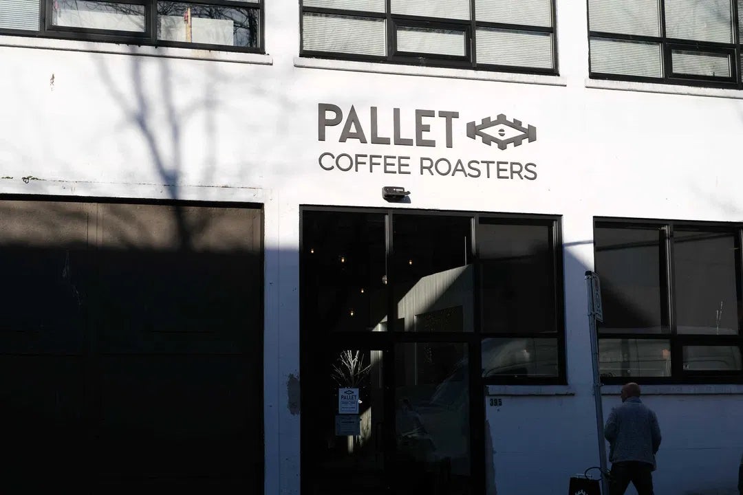 The white brick exterior of the Pallet Coffee Roasters Railtown headquarters, with the Pallet Coffee Roasters sign above the entrance