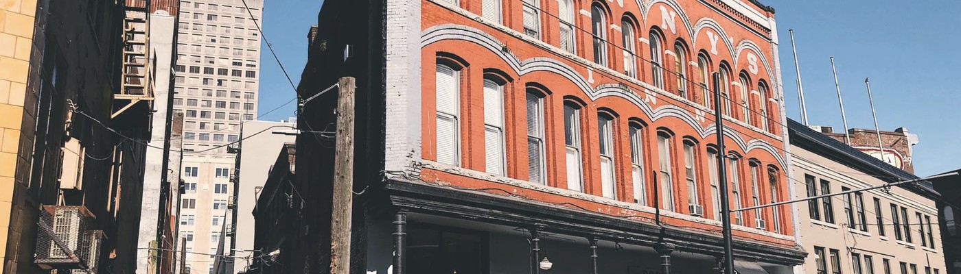 The historic red brick heritage building on Cambie Street housing Revolver Coffee, with faded painted signage on the upper facade